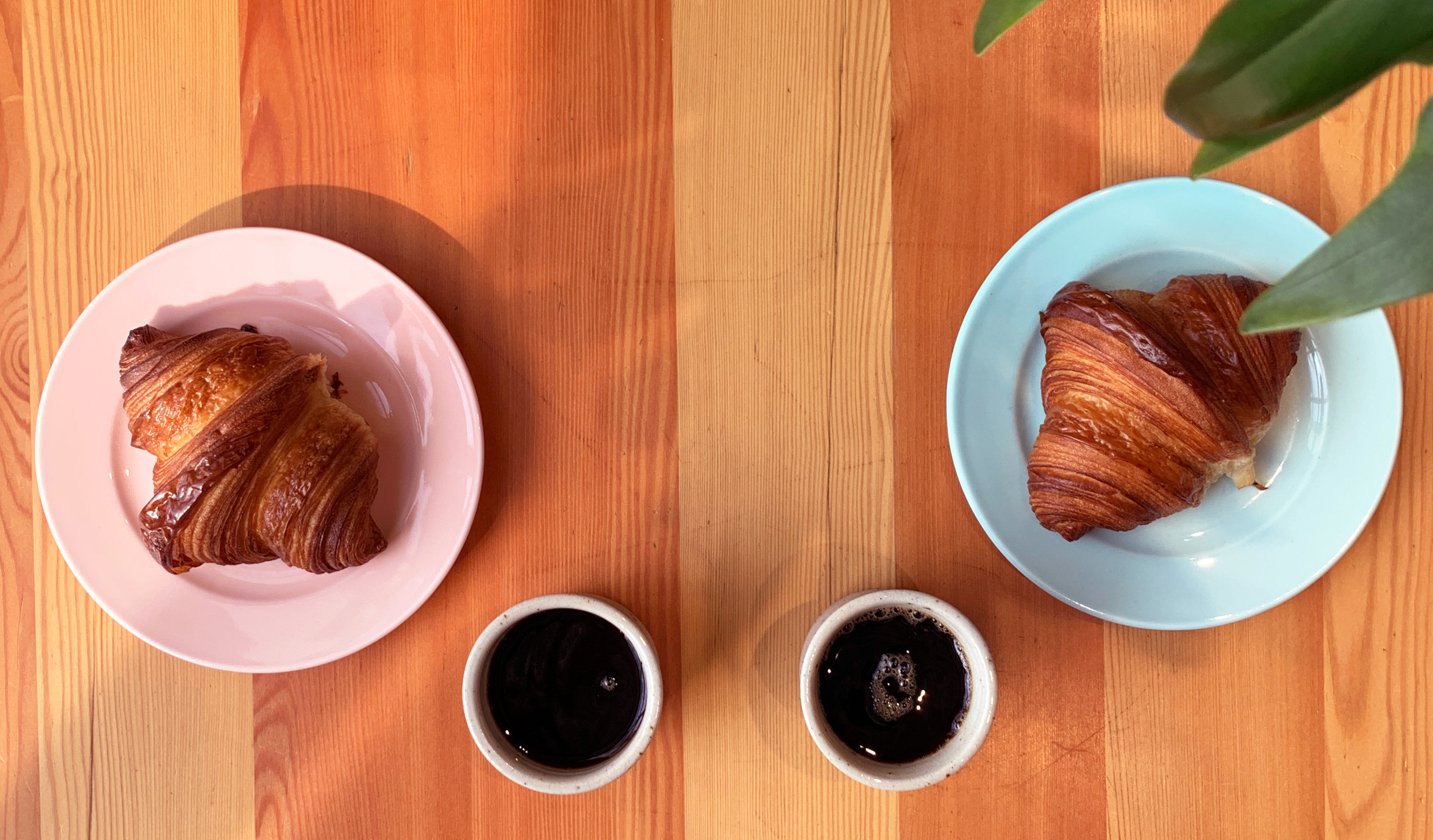To kaffekopper og to croissanter sett ovenfra.