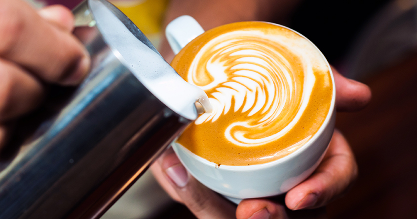 En barista heller melk i espresso for å lage lattekunst