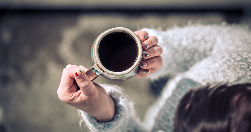 En kvinne holder en kopp med svart kaffe