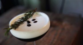 Et cocktailglass med espresso martini. På overflaten av drikken ligger det noen kaffebønner.
