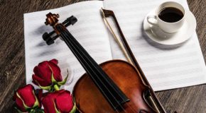 Kaffekantaten: En fiolin, roser og en kaffekopp opp et tomt notehefte.