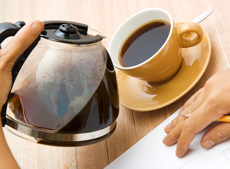 Kaffe helles fra en kaffekanne og over i en kopp.