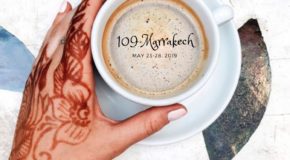 Hånd dekorert med henna-tatovering holder rundt en kaffekopp.