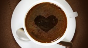 En kaffekopp med hjertemønster i kaffen.
