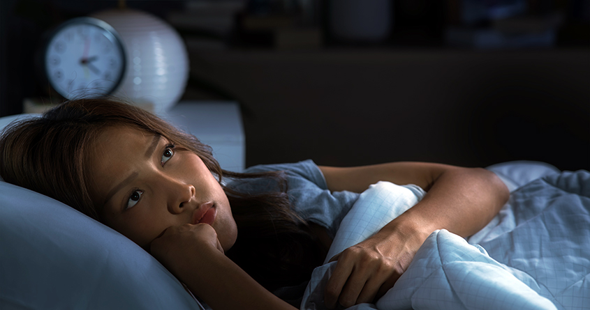 En ung kvinne ligger i sengen midt på natten uten å få sove