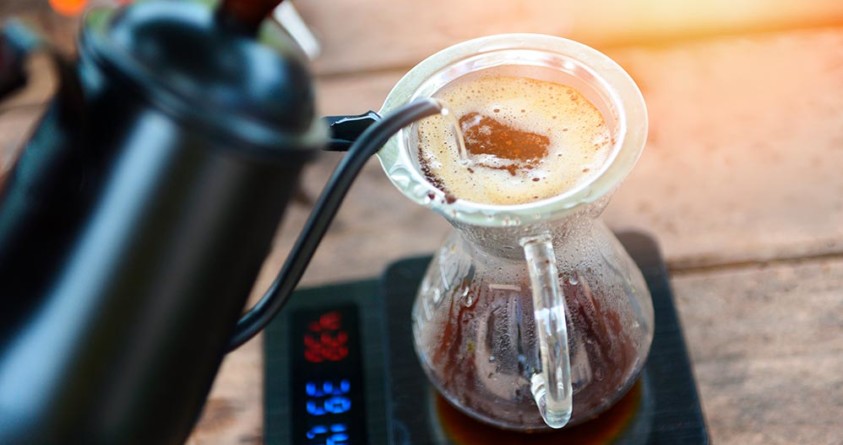 Vann helles over kaffe i en filterbeholder.