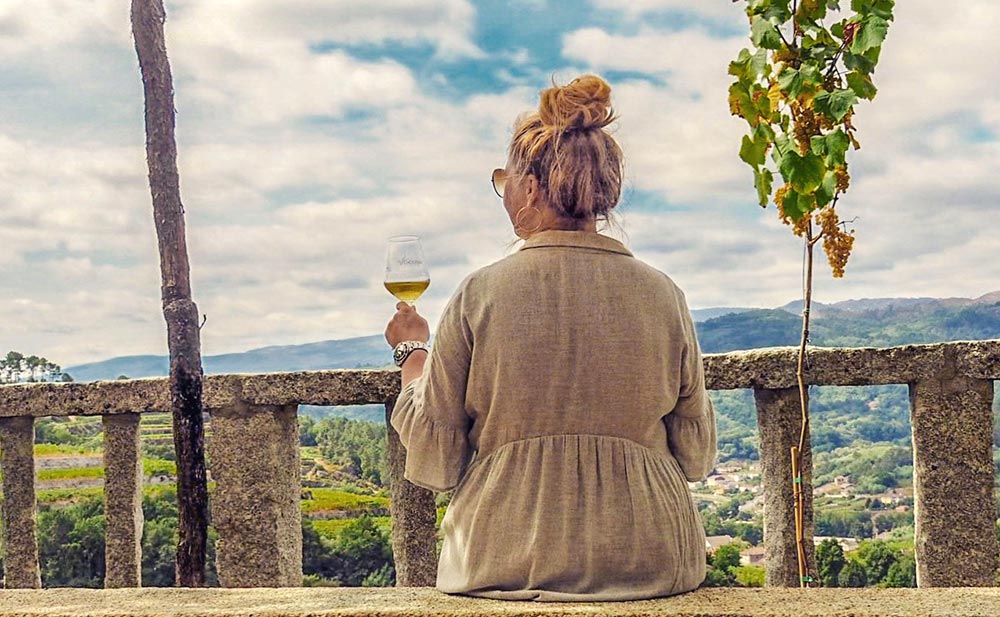 TravelQueen ser utover landskapet med et vinglass i hånden.