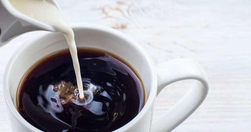 Melk helles i en kopp med svart kaffe.