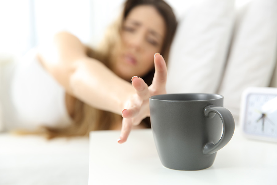 B-menneske? En kvinne som ligger i sengen strekker seg etter en kaffekopp på nattbordet.
