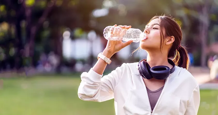 En åpenbart tørst kvinne drikker vann fra en vannflaske