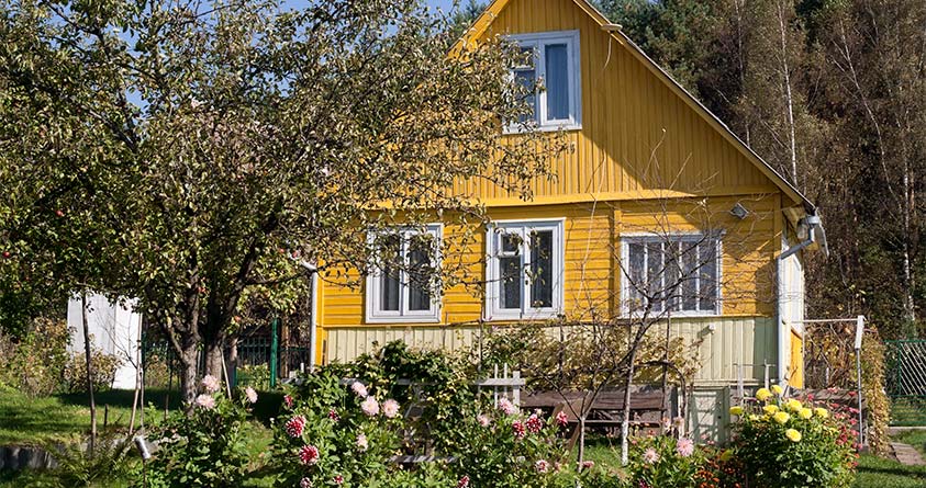 Et gult hus med en hage foran.