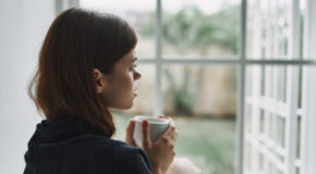 En kvinne med MS-relatert utmattelse drikker kaffe og ser ut av vinduet.