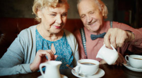 Et eldre ektepar sitter og drikker kaffe sammen