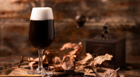 Et glass med twisted coffee, kaffe med smak av whisky eller om, står på et bord sammen med noen høstblader.