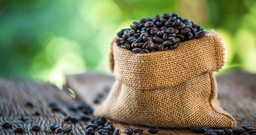 En pose med kaffe står på et bord ute i naturen.