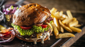 En hamburger ligger på et serveringsbrett sammen med pommes frites.