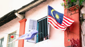 En malaysisk flagg flagger i vinden utenfor et hus i Malaysia.