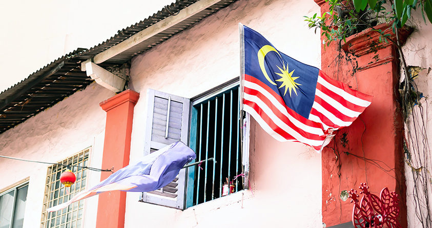 En malaysisk flagg flagger i vinden utenfor et hus i Malaysia.