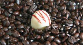En hvit sjokolade ligger på en seng av kaffebønner.