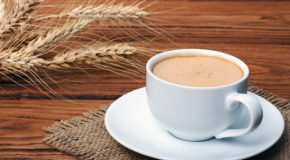 En kopp med caffè d’orzo står på et bord sammen med byggkorn.
