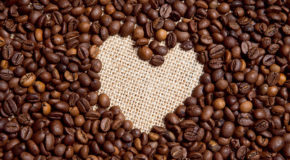 Kaffebønner ligger på et bord, med et negativt hjerte inni seg.