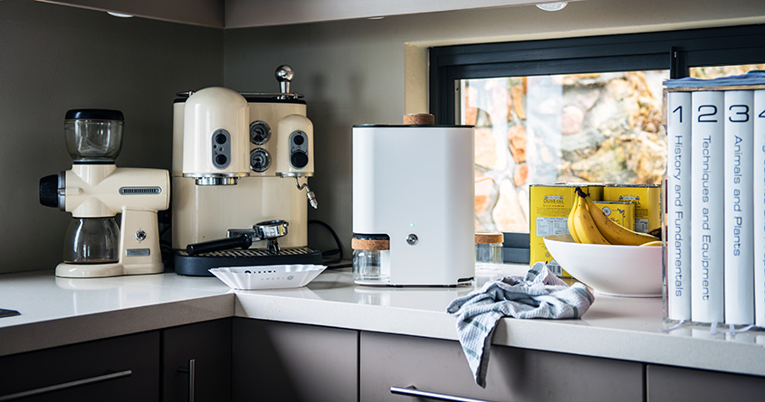 En IKAWA At Home hjemmebrenner står på kjøkkenbenken sammen med annet kaffeutstyr.