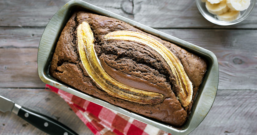 Et bananbrød står nystekt på et bord, fortsatt i brødformen