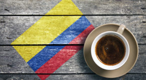 En kaffekopp står på et bord med det colombianske flagget.