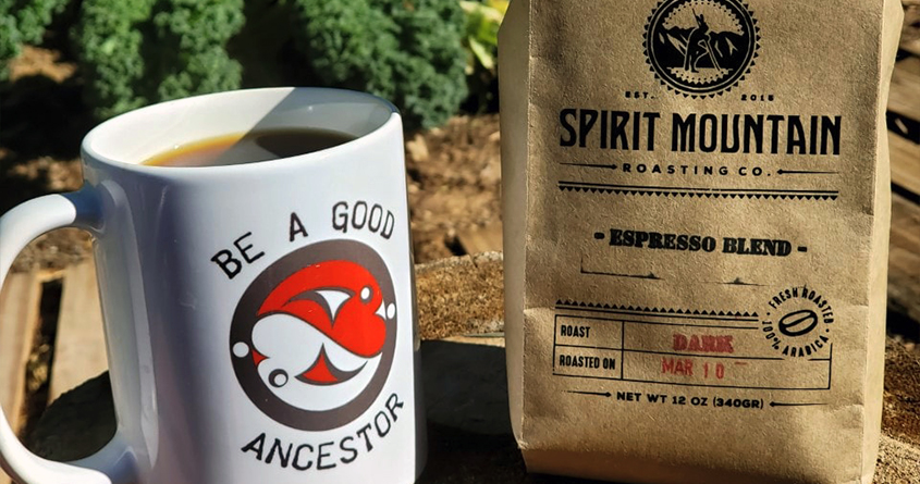 En pose med kaffe fra Spirit Mountain Roasting står i solen ved siden av en kopp med kaffe