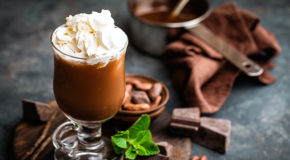Et glass med kaffe mokka står på et bord sammen med sjokolade