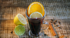 Et glass med kaffe, en sitronskive og en appelsinskive står på et bord