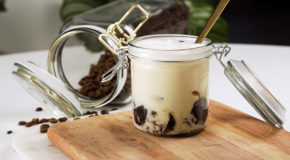 Et glass med vaniljemelk og hjemmelaget kaffegelé står på et bord