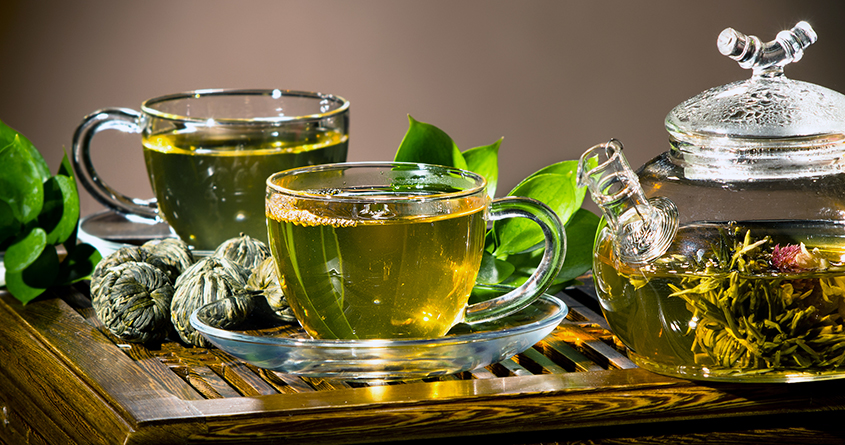 Grønn te er brygget i en glasskanne og helt over i to glasskopper