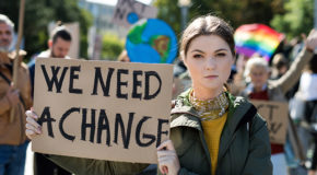 En kvinne demonstrerer for klimaet, med et skilt som sier "we need a change"