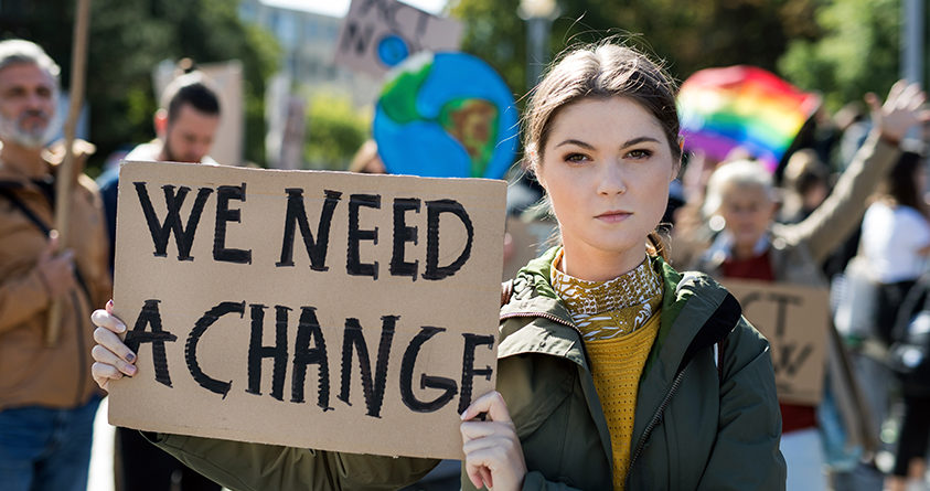 En kvinne demonstrerer for klimaet, med et skilt som sier "we need a change"