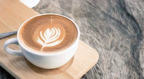 En kopp med cappuccino står på en skjærefjøl på en benk