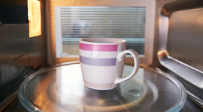 En kopp med kaffe står i en mikrobølgeovn for å gjenoppvarmes