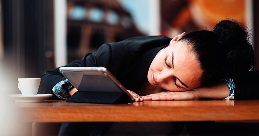 En kvinne har lagt hodet ned på bordet og ser ut til å sove