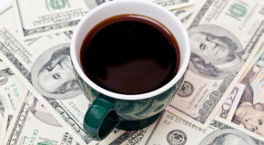 En grønn kopp med kaffe står oppå mange pengesedler.