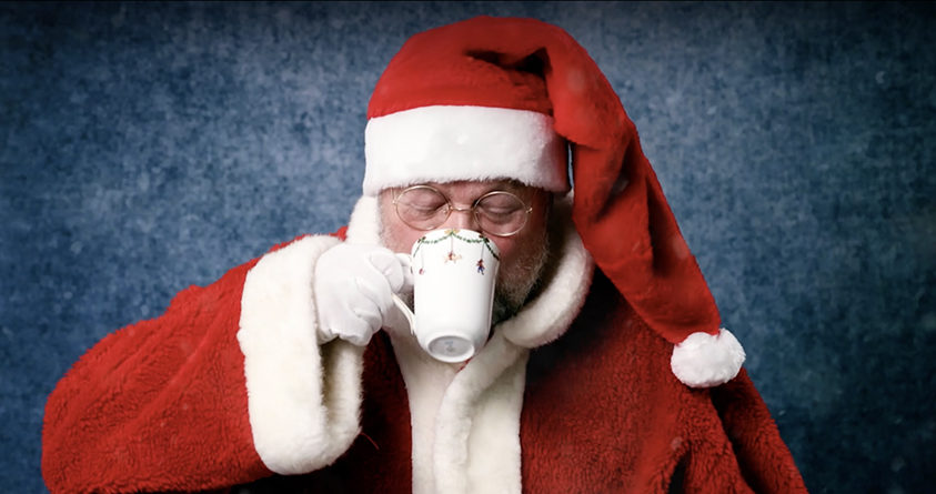 Julenissen drikker kaffe fra en julekopp