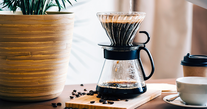 En håndbrygger med kaffe står på et bord