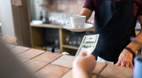 En person kjøper kaffe og gir penger til en barista
