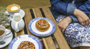 En kvinne sitter på en kafé og nyter kaffe og kanelboller – såkalt fika