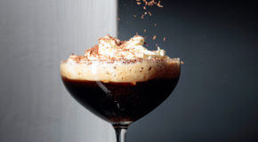 En person strør revet sjokolade over et glass med Spanish Coffee 43