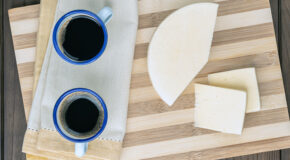 To kaffekopper står på en fjøl sammen med en ost