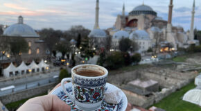 En person holder en kopp med kaffe opp mot Hagia Sofia i Istanbul.
