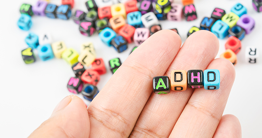 En person holder fire perler i hånda hvor det står ADHD.