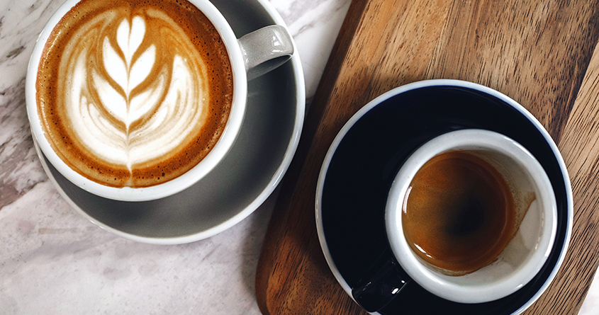 En kopp med espresso og en kopp med cappuccino står ved siden av hverandre