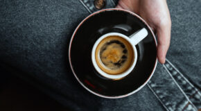 En kvinne holder en svart kopp med espresso på fanget
