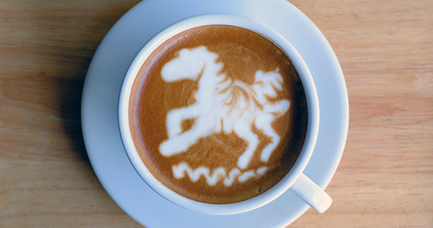 Lattekunst av en hest er laget i en kopp med kaffe